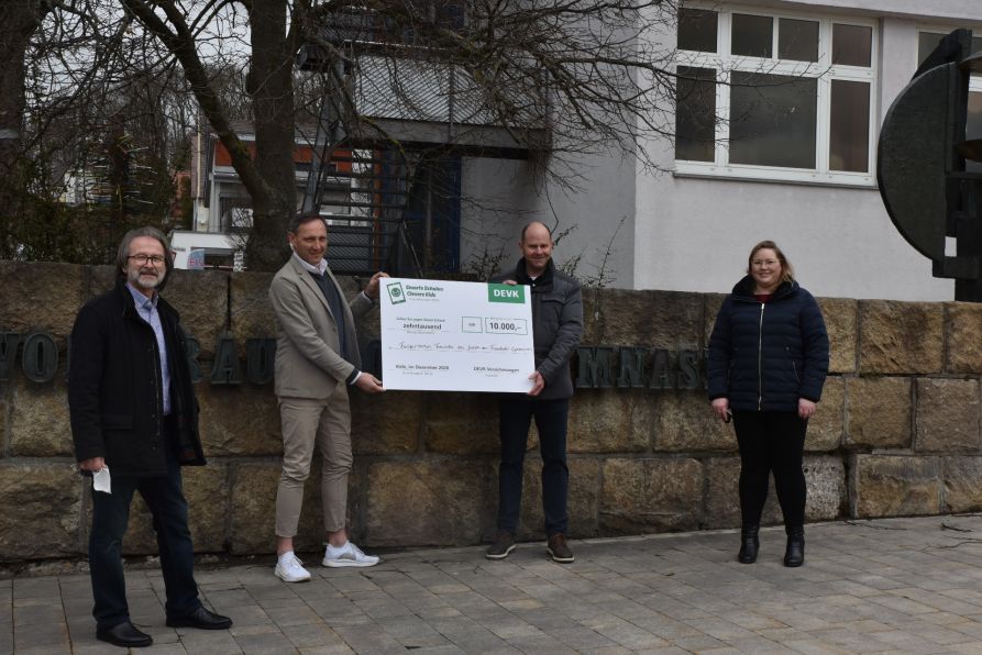 Die Vertreter der DEVK-Versicherungen Markus Kulzer und Jennifer Wagner (r.) überreichen den symbolischen Spendenscheck in Höhe von 10.000 Euro an den Fördervereinsvorsitzenden StD a. D. Christian Nowotny (l.) und Schulleiter OStD Uwe Mißlinger.