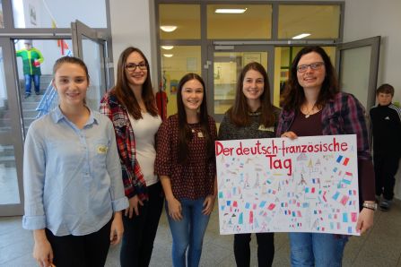 Katharina Götz, Luca Gacs, Laura Sperlich und Maria Schmidbauer mit Schulleiterin Claudia Urban und dem von den Schülern gezeichneten Plakat 