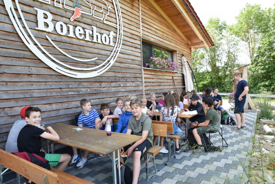 Die Schülerinnen und Schüler machen Pause vor dem Hofladen des Boierhofs.