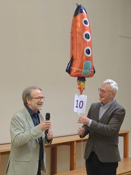 Christian Nowotny überreicht Prof. Burkert ein Geschenk anlässlich seines zehnten Vortrags an unserer Schule.